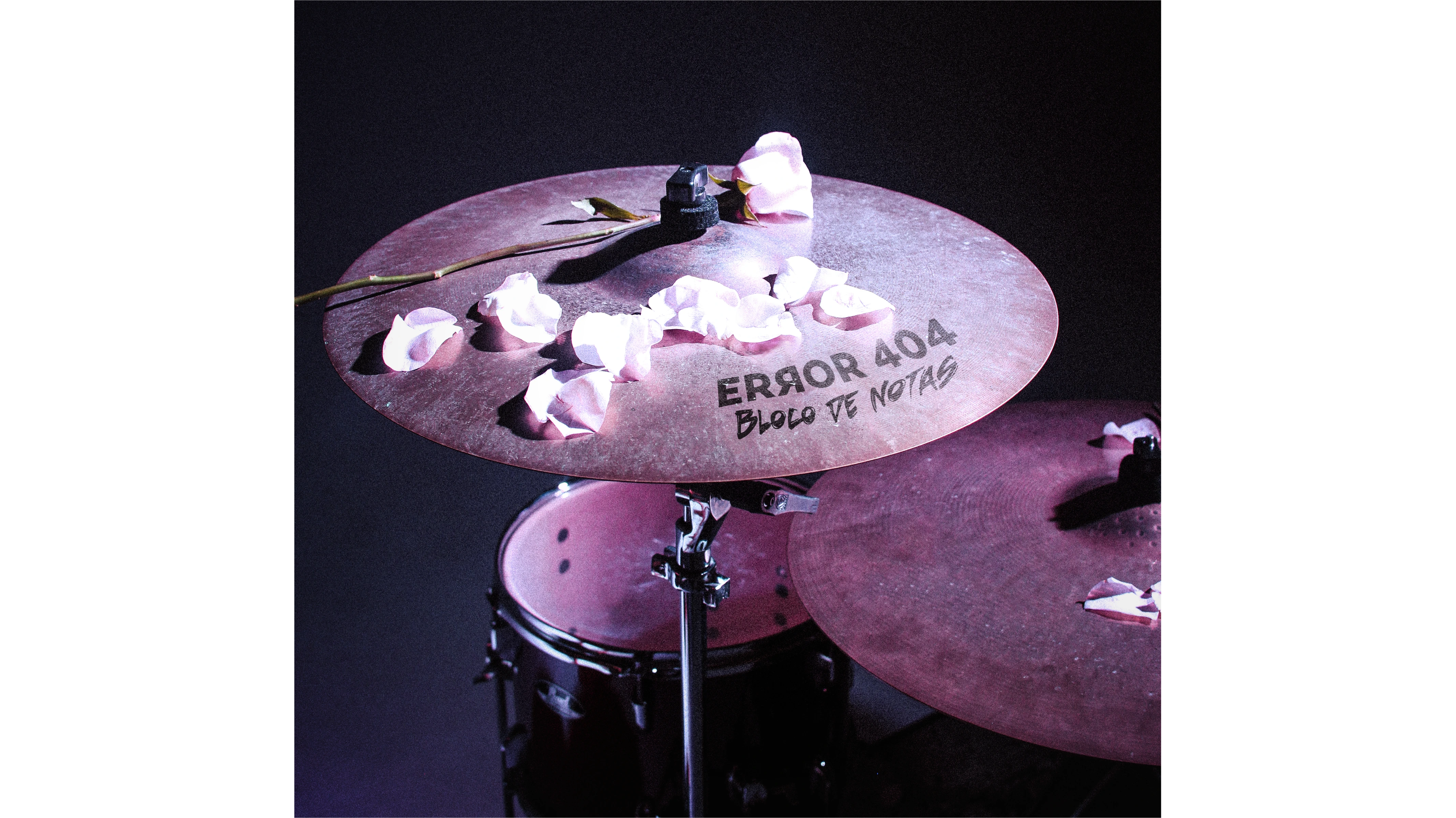 Capa do Single 'Bloco de Notas' com uma bateria escrita o nome da banda e do single nela, com pétalas de rosa por cima